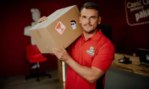 Kurier DPD z paczką na ramieniu. Zastanawiasz się, ile zarabia kurier DPD? Ten pracownik wygląda na zadowolonego z pracy.