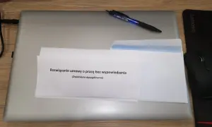 Koperta z dokumentem "Rozwiązanie umowy o pracę bez wypowiedzenia (Zwolnienie dyscyplinarne)" na laptopie.