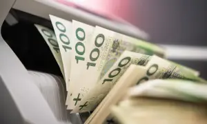 Stos banknotów 100 zł w maszynie do liczenia pieniędzy.