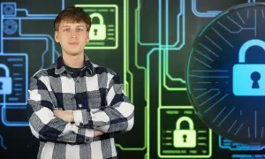 Młody mężczyzna w kratę stoi na tle cyfrowych zamków i obwodów.