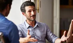 Dwóch mężczyzn rozmawia, jeden gestykuluje rękami.