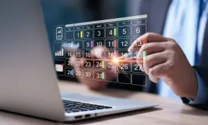 Biznesmen planuje pracę, zastanawiając się, ile godzin to 1/4 etatu. Kalendarz cyfrowy wyświetla dni miesiąca.