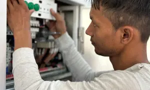 Elektryk montuje panel sterowania w skrzynce elektrycznej.