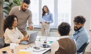 Zespół omawia nowe projekty, planując zmianę pracy na bardziej ekologiczną. W tle widać model turbiny wiatrowej.