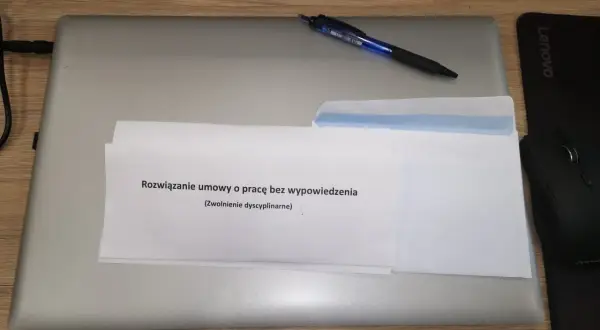 Koperta z dokumentem "Rozwiązanie umowy o pracę bez wypowiedzenia (Zwolnienie dyscyplinarne)" na laptopie.