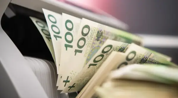 Stos banknotów 100 zł w maszynie do liczenia pieniędzy.