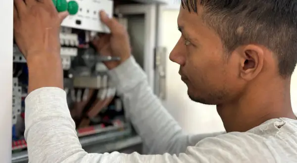 Elektryk montuje panel sterowania w skrzynce elektrycznej.