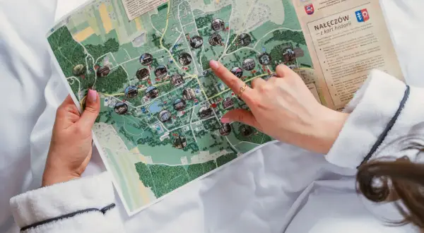 Kobieta w szlafroku przegląda mapę Nałęczowa z zaznaczonymi atrakcjami.