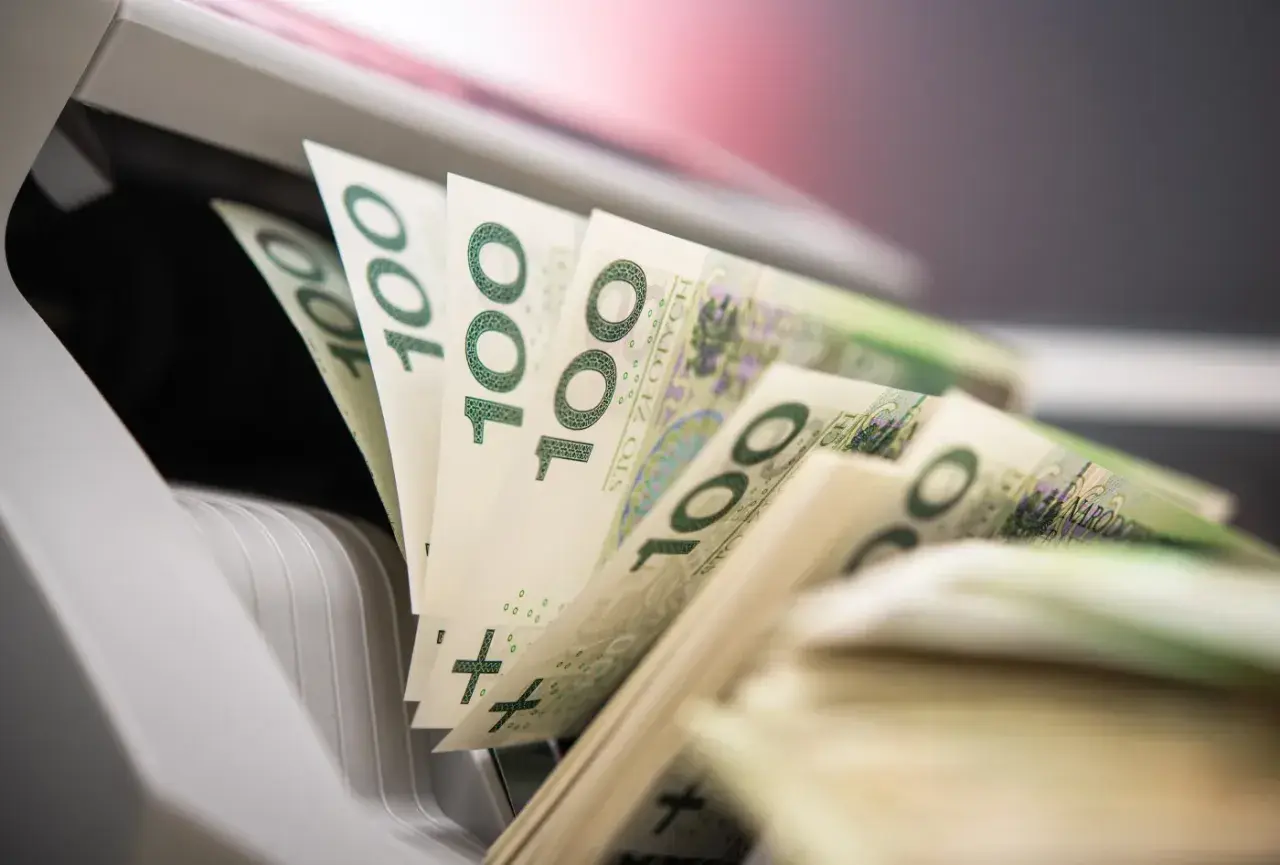 Stos banknotów 100 zł w maszynie do liczenia pieniędzy.
