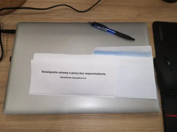 Koperta z dokumentem "Rozwiązanie umowy o pracę bez wypowiedzenia (Zwolnienie dyscyplinarne)" na laptopie.