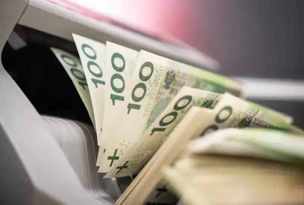Stos banknotów 100 zł w maszynie do liczenia pieniędzy.