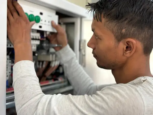Elektryk montuje panel sterowania w skrzynce elektrycznej.