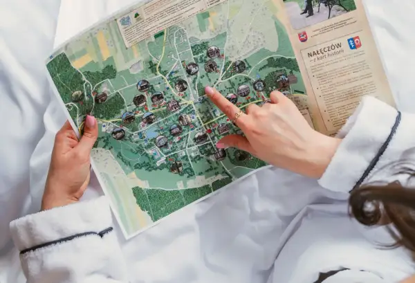 Kobieta w szlafroku przegląda mapę Nałęczowa z zaznaczonymi atrakcjami.